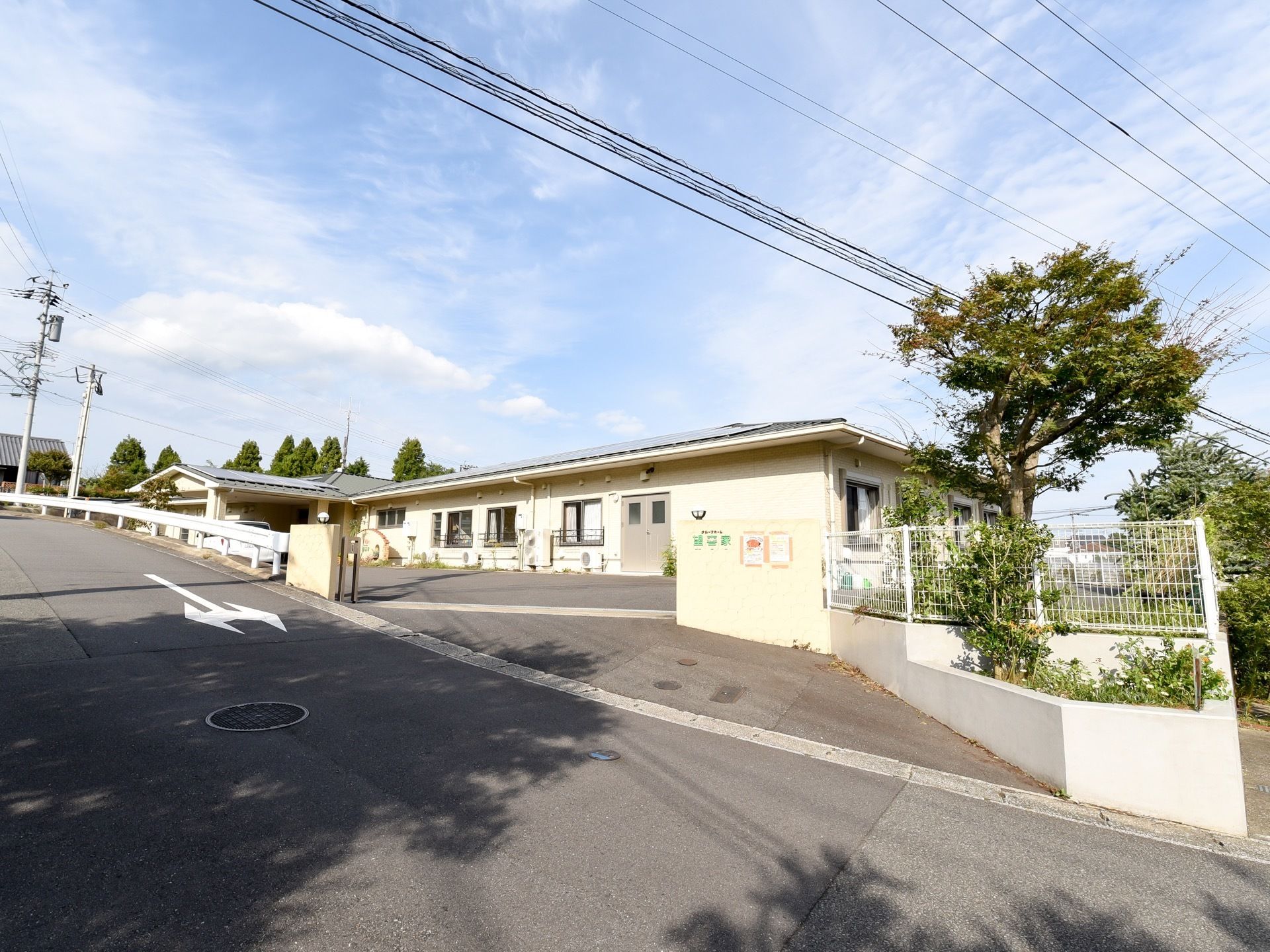 ベージュ色の平屋建ての施設である。敷地はフェンスで囲まれている。エントランスには、屋根が設置された車寄せがある。