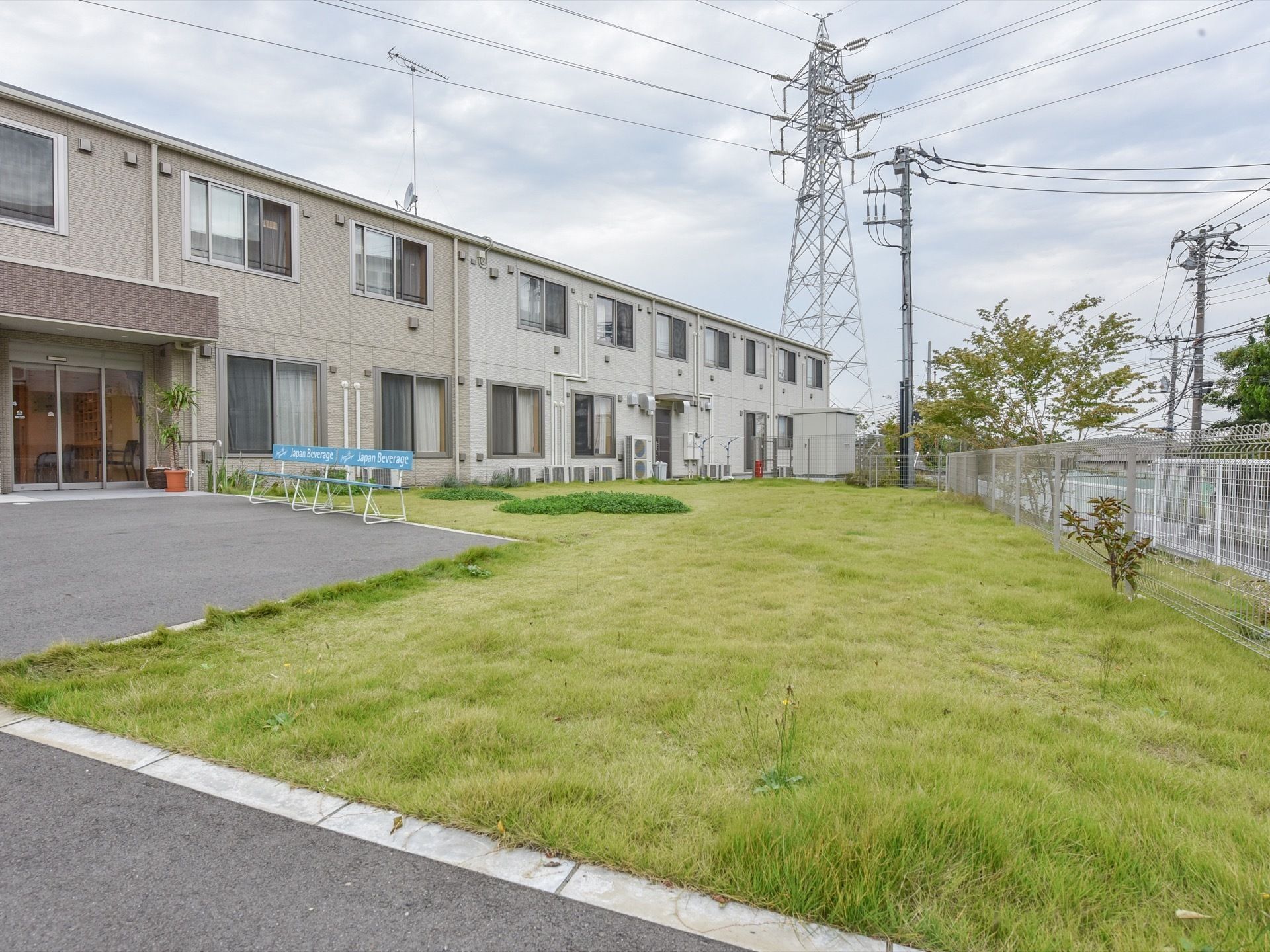 施設の敷地内には広く確保された庭があり、綺麗な芝生が敷き詰められている。敷地の周辺には、白いフェンスが取りつけられている。