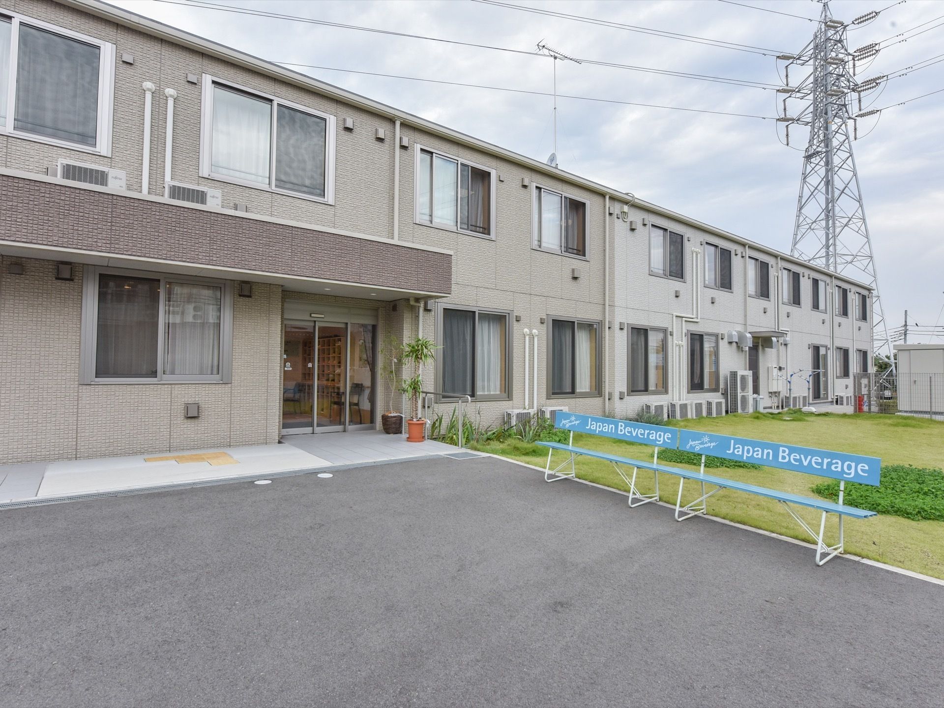 施設は横に長い2階建ての施設になっており、外壁はグレーで統一されている。玄関前には、ベンチが2つ置かれている。