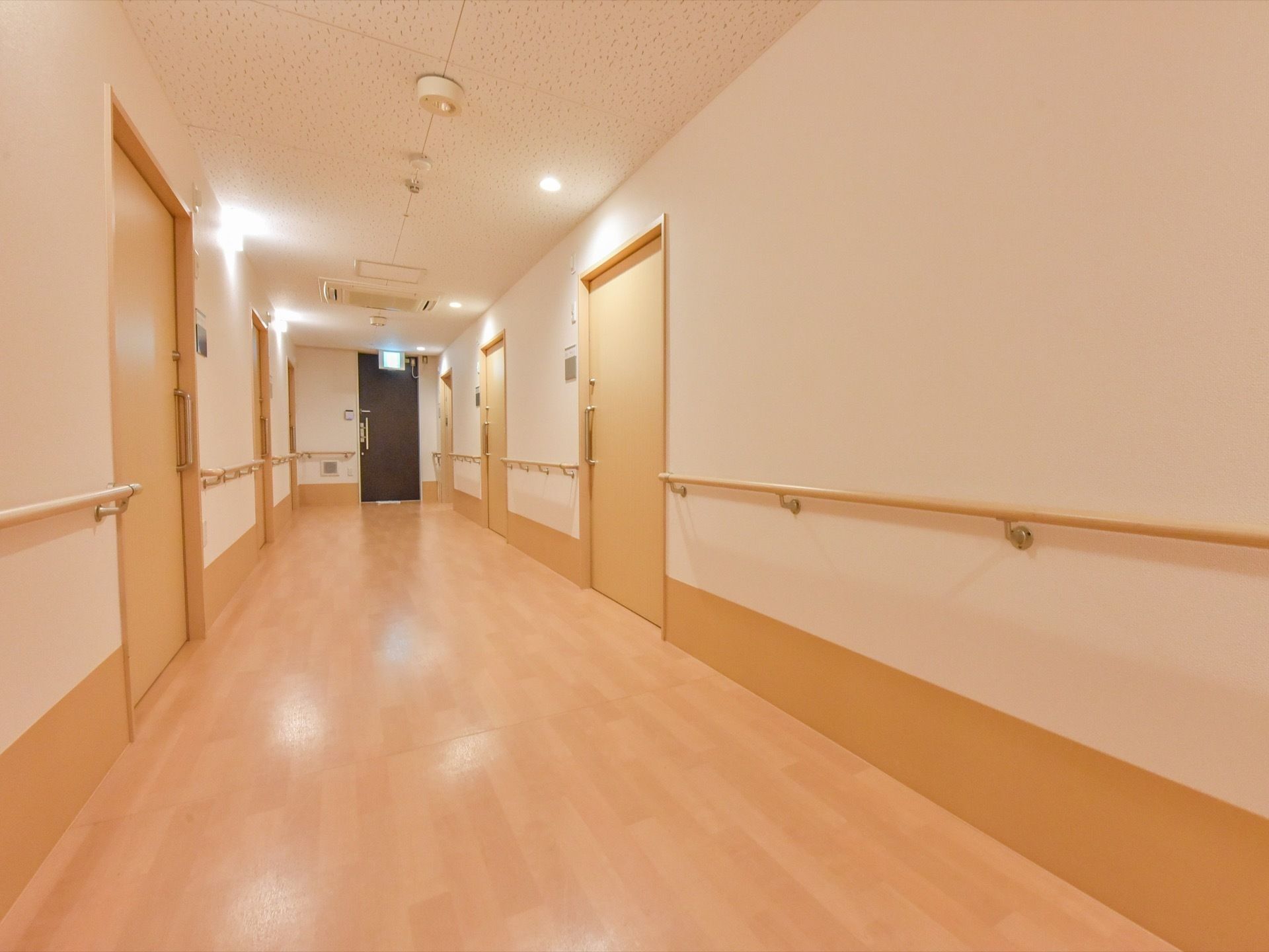 入居者様用の居室前の廊下は幅が広く、壁に手すりが取りつけられている。居室の扉は、大きな引戸になっている。