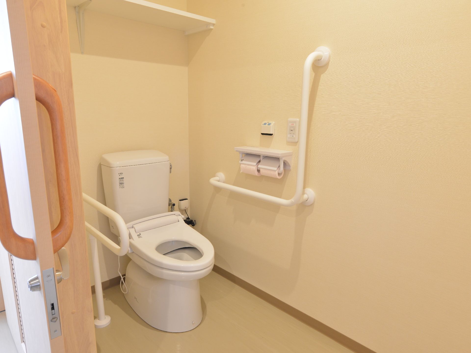 居室のトイレは水洗トイレ。扉は横にスライドし広く開閉することができる。壁と便器の隣には手すりがあり、呼び出しスイッチも設置されている。