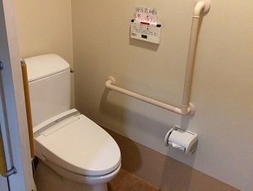 壁にＬ字型の手すりがあるトイレ。入口は引き戸になっている。