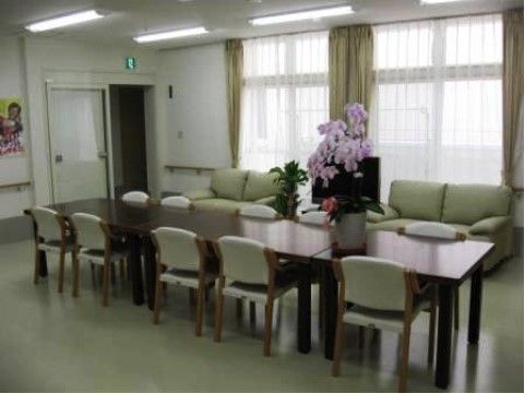 数台のテーブルが並べて置いてあり、テーブルの上に花が飾られている。天井に設置された蛍光灯が点灯している。