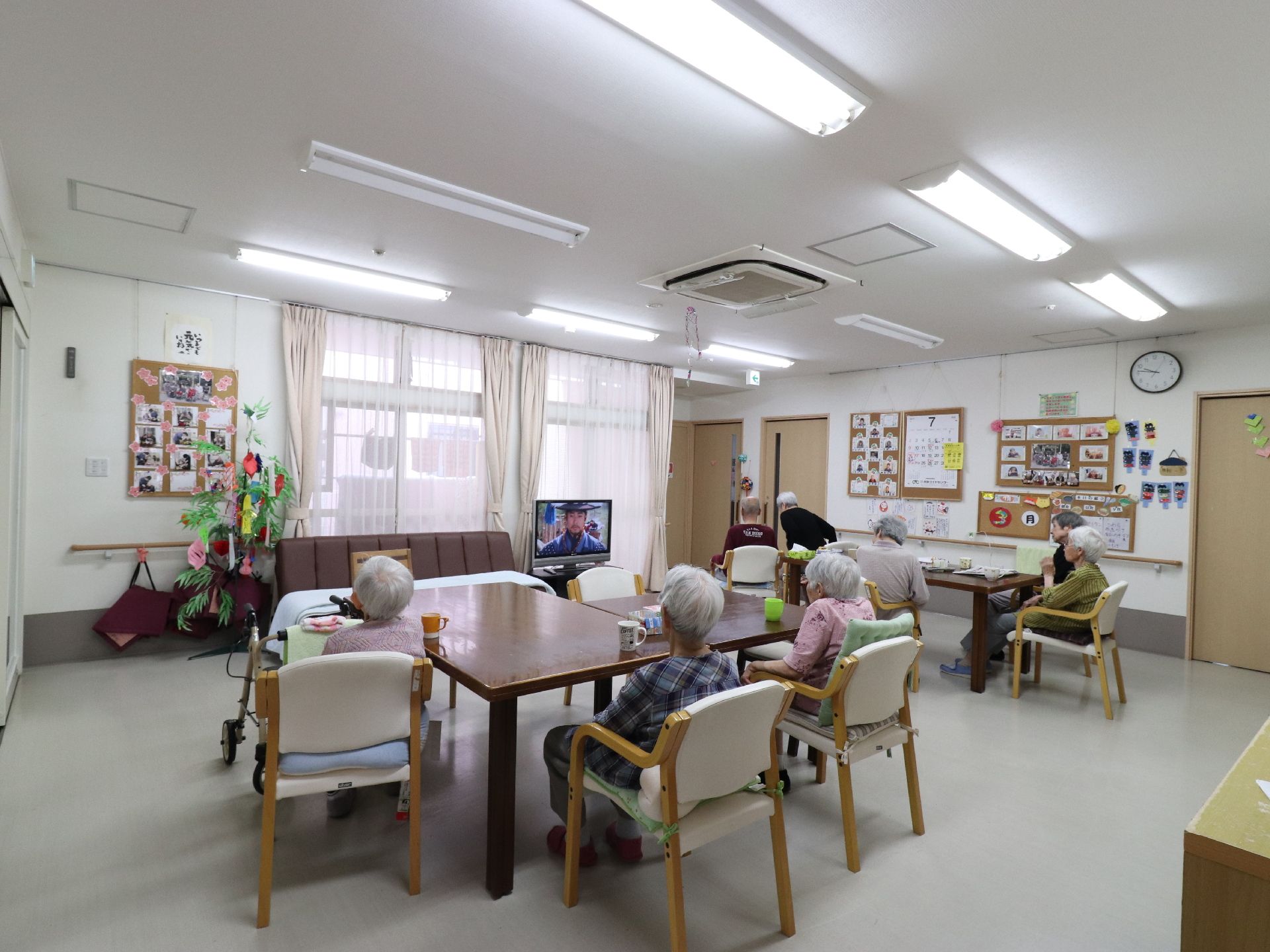 お茶を机に置いて、利用者の方数名がテレビを見ている。話をしている方もおられ、自由に過ごすことができる。