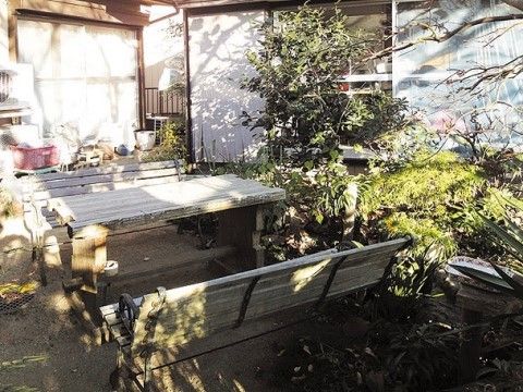 明るい陽射しが注ぐ日中の木製のテーブルセットが設置された庭