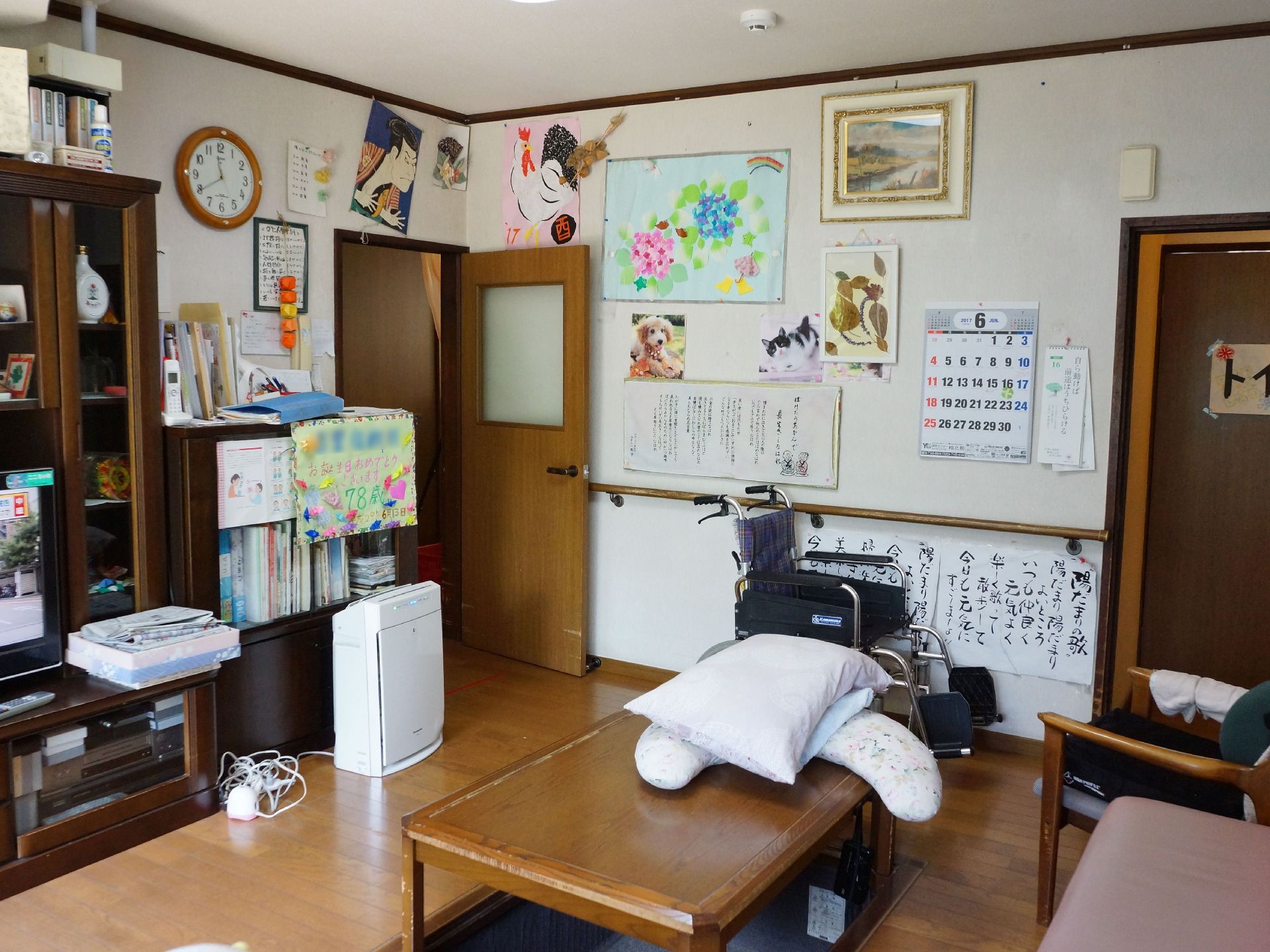 リビングルームの壁には手すりがあり、絵画や写真が飾られている。また室内には空気清浄機が置かれている。