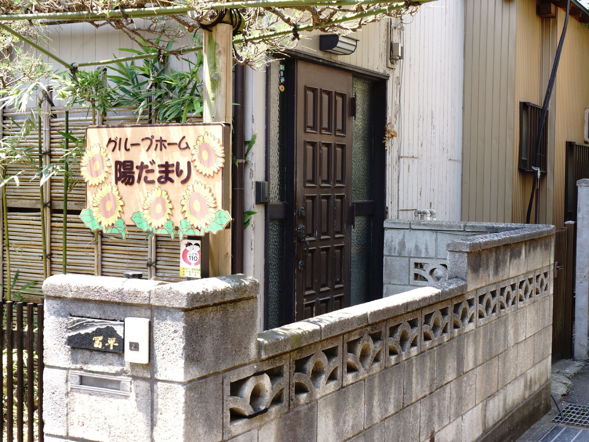 エントランスには施設名が書かれた看板を設置している。また塀には郵便受けがあり、インターホンが備え付けられている。