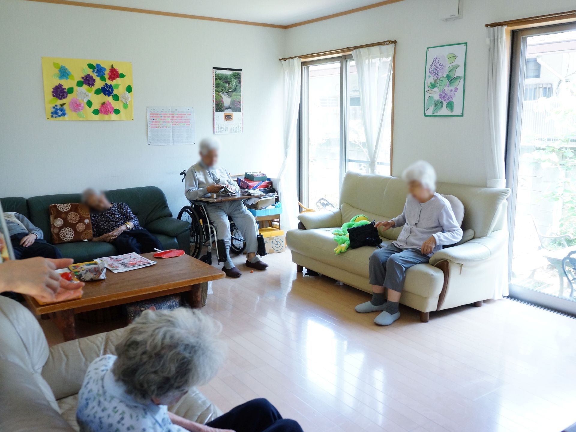 リビングルームにはソファがあり、テーブルが置かれている。また室内には大きな窓があり、カーテンが取り付けらている。