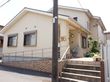 グループホームの建物は2階建てで、前の道路よりも高い場所に建っている。入り口にはスロープと階段があり、手すりを設置している。