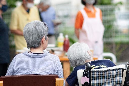 車椅子に座って屋外レクを楽しむ高齢者