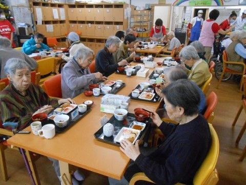 テーブルを囲んで食事を楽しむ高齢者