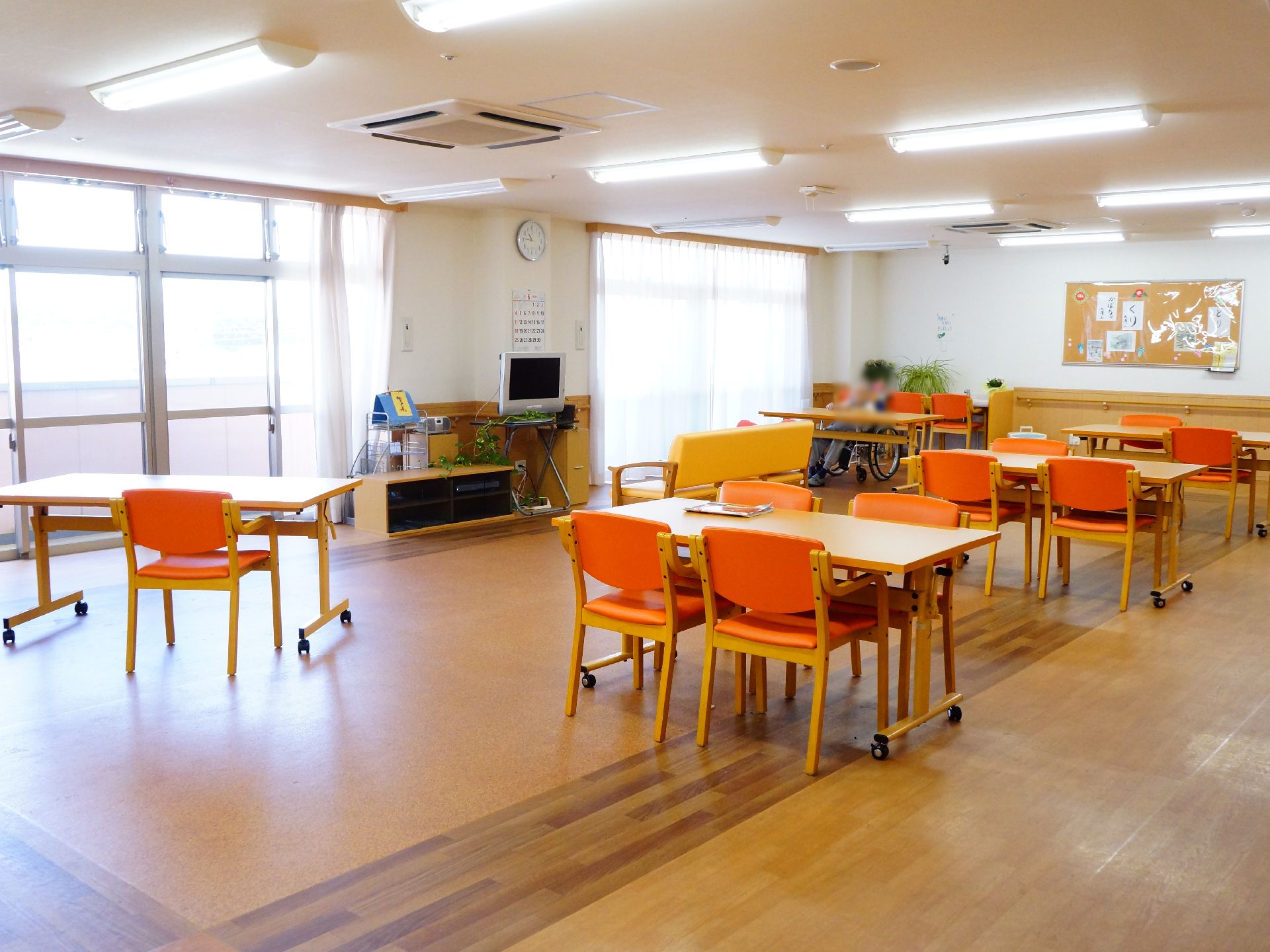 窓が大きく明るい食堂には、テーブルと椅子が並んでいる。窓側の中央付近にテレビがあり、ソファに座ってくつろぎながら見ることができる。