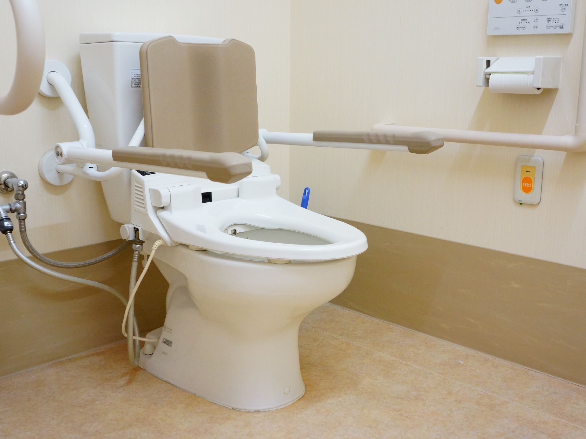 車椅子用の洋式トイレには、手すりのほかに背もたれと肘掛けがついており、姿勢を安定させることができる。手すりの下には呼び出しボタンがある。