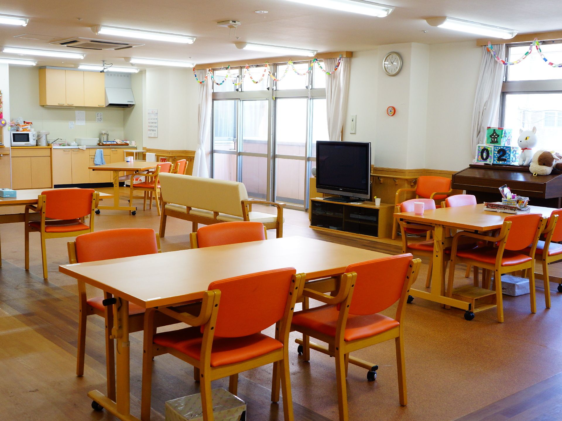 消防設備側から食堂の奥を見ると、事務室の隣に簡易的なキッチンがある。上には換気扇と戸棚、下にはシンクや戸棚、電子レンジ、ポットがある。