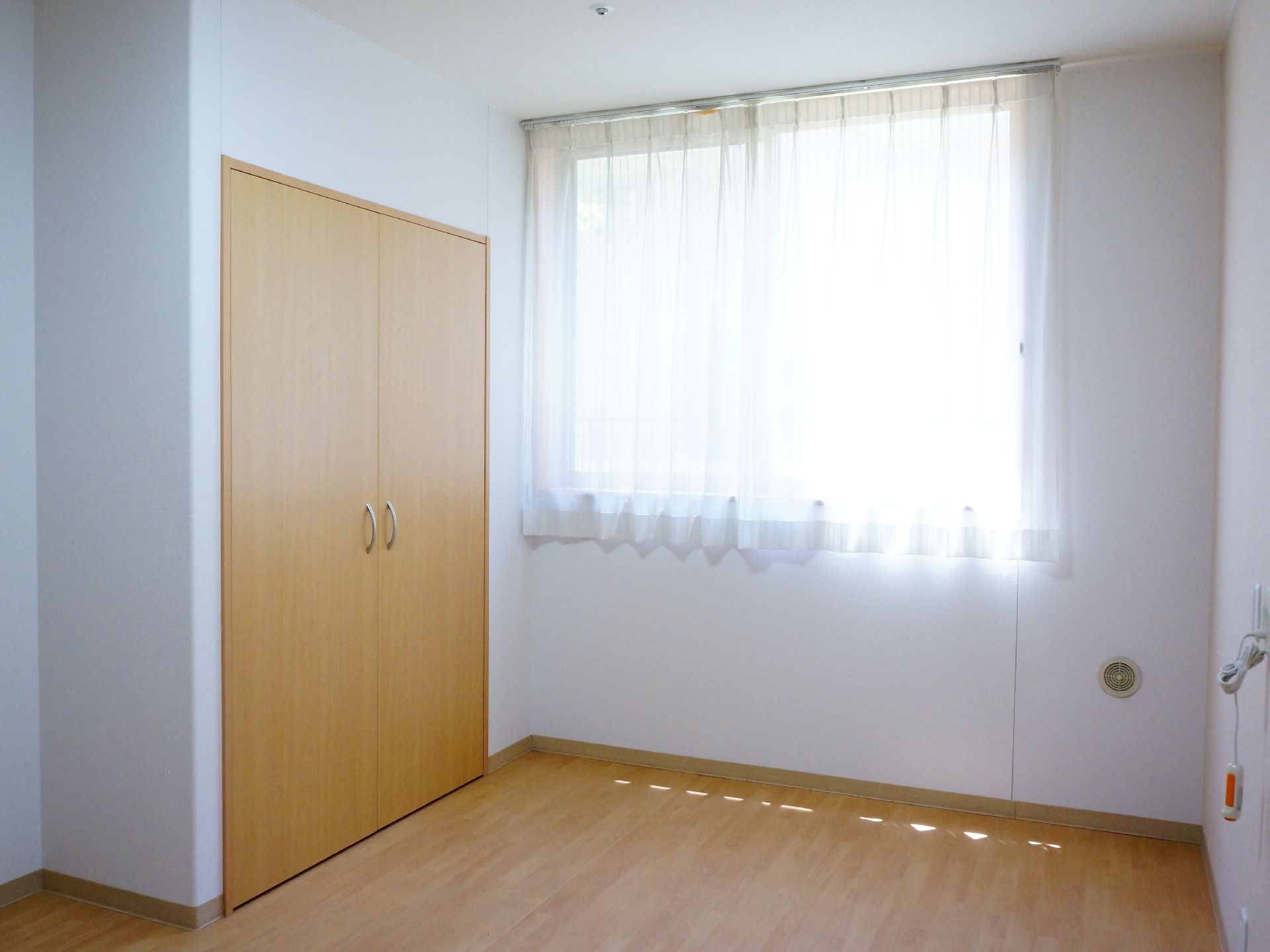 部屋の左側にはクローゼットがある。奥には窓がありカーテンが付いている。日当たり良好でとても明るく感じる。