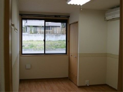 黒サッシの窓の横にクローゼットがついている居室。エアコンが取り付けられている。落ち着いた配色でシンプルな部屋となっている。