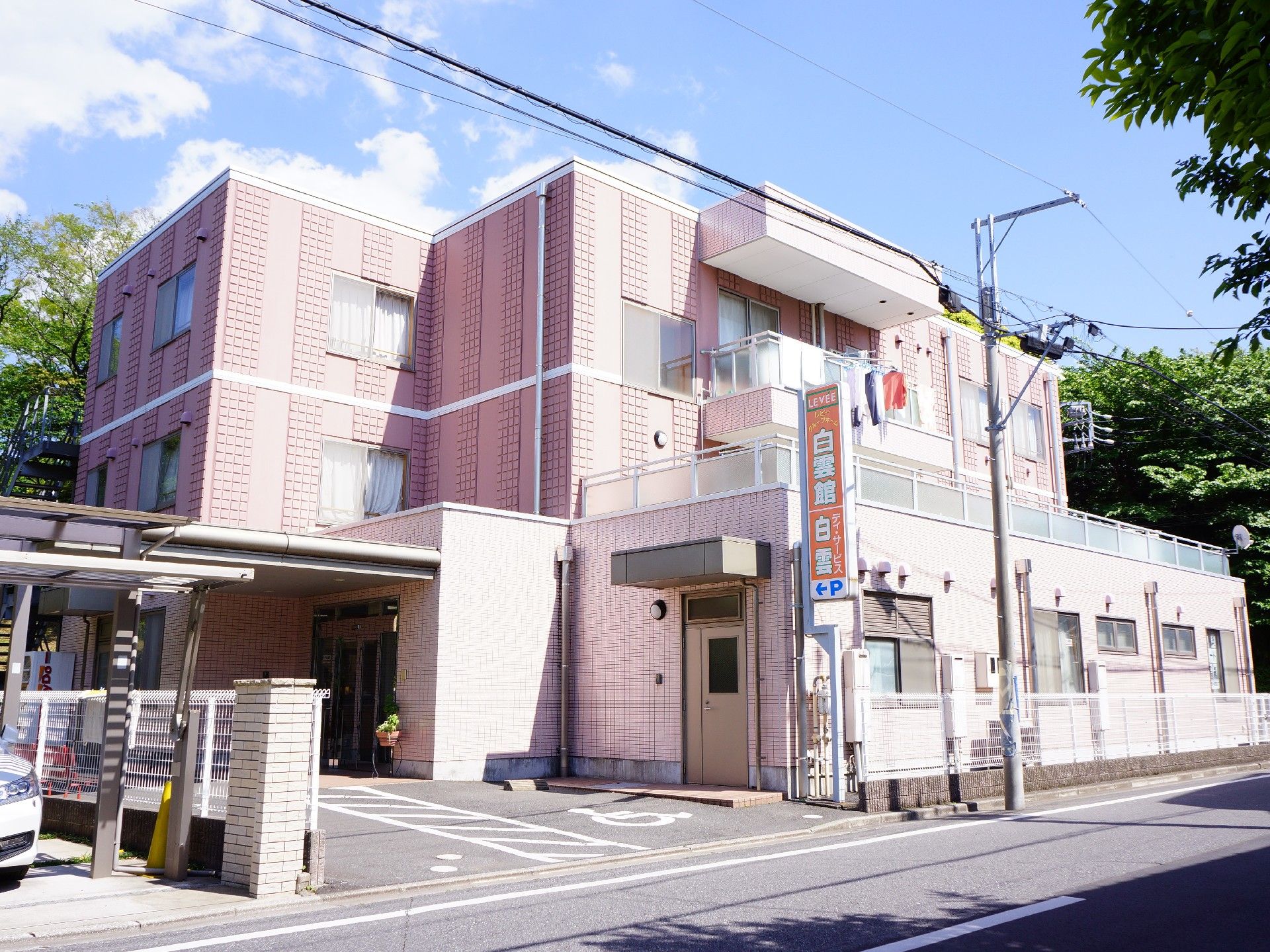 オレンジの看板が目印の建物。敷地内に駐車スペースを設けている。