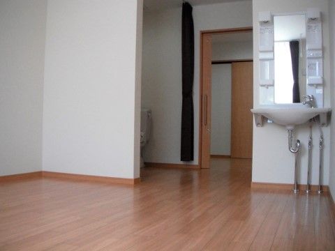 スライド式の扉を通じて、フローリングの敷かれた明るい居室内に歩を進めることができる。室内の一角には鏡付きの洗面台が備え付けられている。