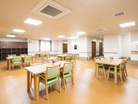 明るい木目調のテーブルにパステルグリーンの椅子が配置されている共有スペース