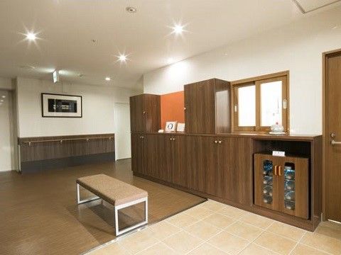 玄関から中に入ると、右側に木製の大きな収納棚があり、その上にはガラスの小窓がある。中央には小さなベンチが置かれている。