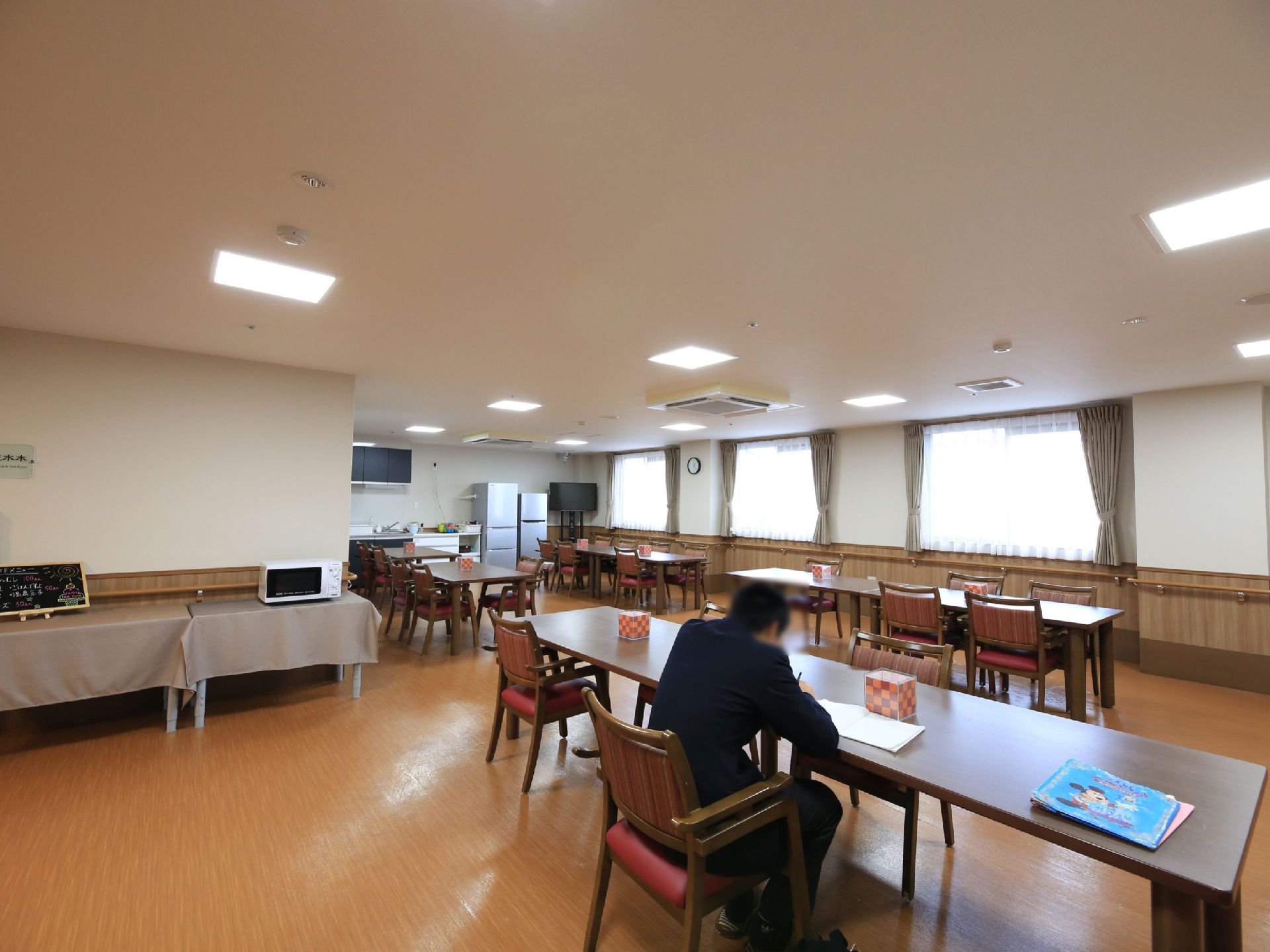 共有スペースは食堂としても使えるリビングダイニングとなっている。壁際の棚には電子レンジやその日のメニューがある。