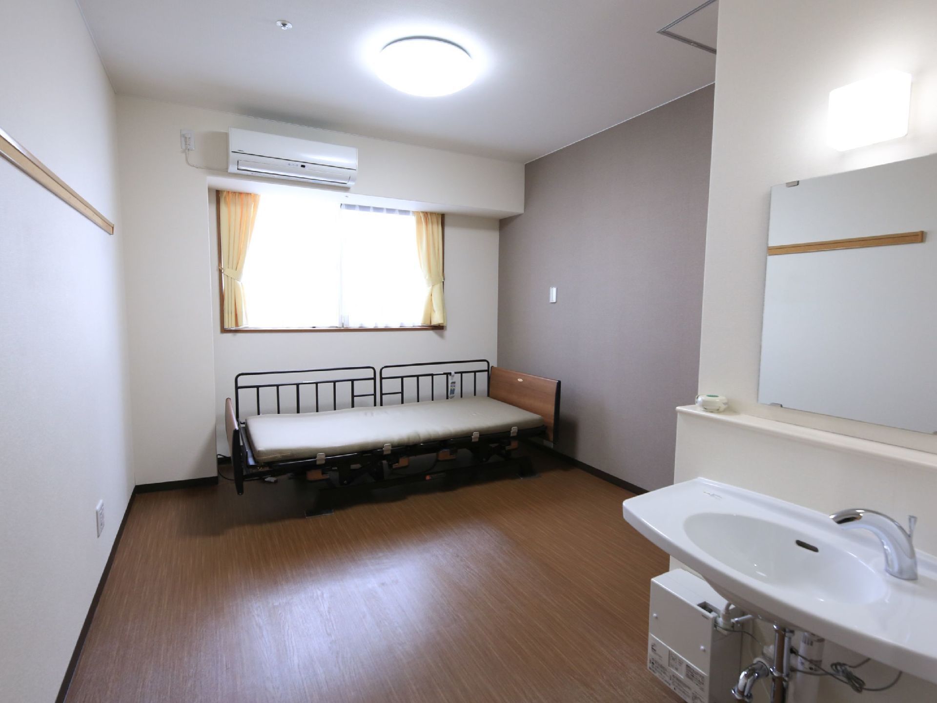 玄関ドア側から見た居室の全体像。ベッドを設置する窓際の壁が、収まりが良くなるようそれに合わせて凹んだ形になっている。