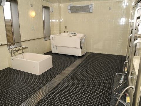浴室暖房乾燥機が取り付けられ個浴槽と介護入浴機器が設置された浴室