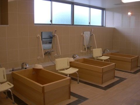 広い浴室に、木製の浴槽が3か所設置されている。浴槽と浴槽の間にはシャワーや鏡、シャワーチェアなどが備えてある。