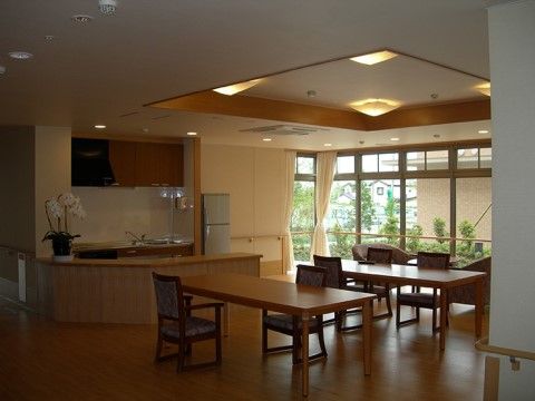 木製のダイニングテーブルと肘掛けが付いた椅子が置かれており、奥のほうにはソファも用意されている。温かみのある照明や空調が取り付けられている。