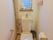 トイレは洋式で便器に向かって左側に手すりが設置されている。窓際にはトイレの掃除道具が置かれている。また、ゴム手袋も備え付けてある。