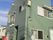 戸建てのような建物は、外壁が深い緑色に塗られている。小規模で、家庭的な雰囲気がわかる。周囲は緑も多く落ち着いた環境である。