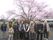 入居者様の団体が桜の樹の下で記念写真を撮っている。外出時はスタッフも同行するため、不安なく外出できる。