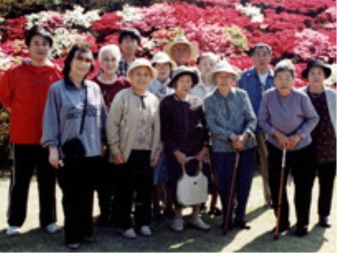 色とりどりのツツジの前で記念撮影する入居者たちと付き添いの職員