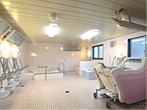手すりが付けられた大きな浴槽と機械浴槽の設備があるタイル張りの浴室