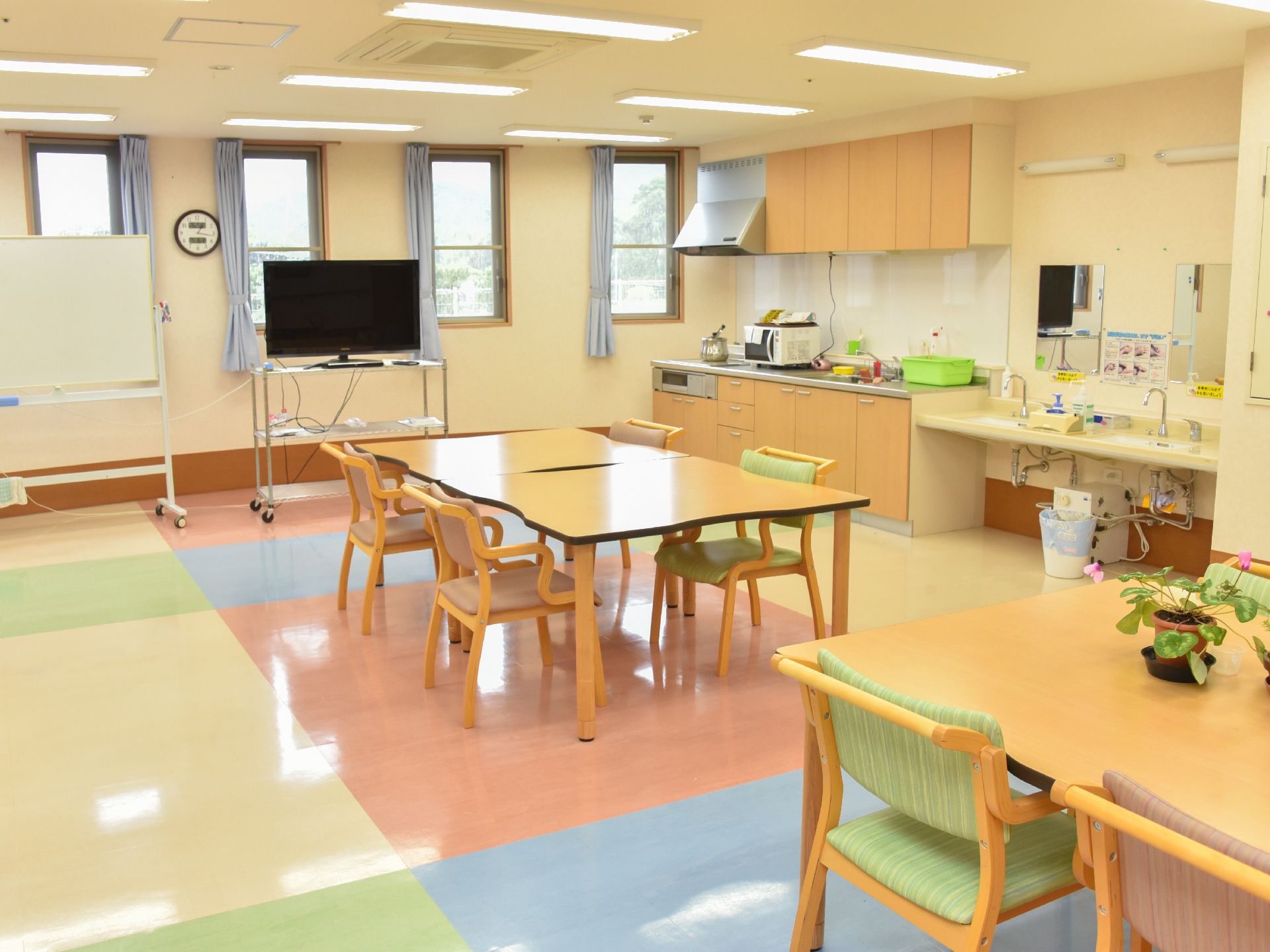 明るく開放的な食堂に、複数の椅子テーブルが並べられている。キッチンや洗面台も併設されているのが特徴的。