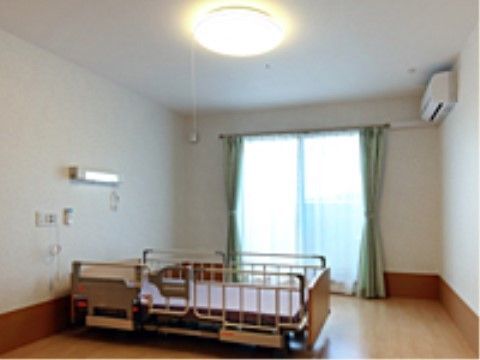 明るくエアコンの付いた室内に置かれたパイプの介護用ベッド