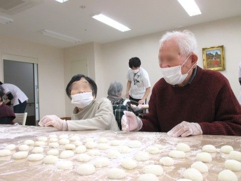 施設の職員に付き添われ、ついた餅を丸める入居者たち