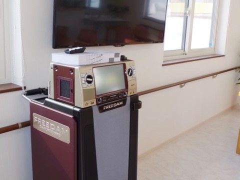 壁に設置されている大きなテレビの下にカラオケ器具が置かれており、その上に曲本やリモコンが用意されている。