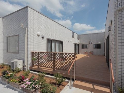 広い柵付きのウッドデッキとその前で花を咲かせる鉢植え
