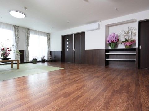 壁の棚やテーブルなどに様々な鉢植えの花が飾られた広い部屋