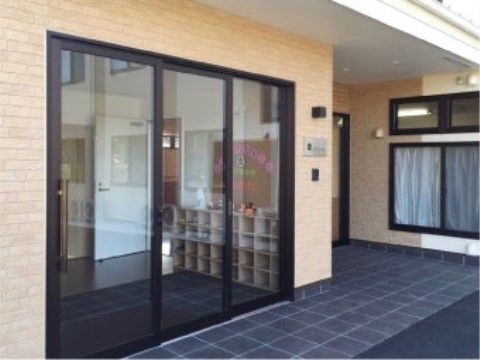 ナチュラルベージュの壁の高齢者向け住宅入り口のガラスの自動ドア