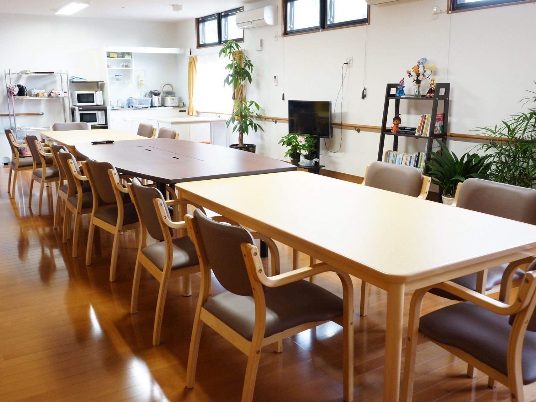共有スペースの奥に、キッチンがある。炊飯器や電気ポット、電子レンジが置かれている。テーブルや椅子があり、テレビも設置されている。