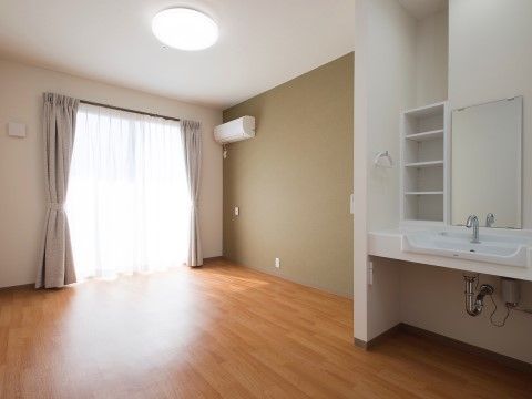 カーテンの開いた窓から光が入る洗面台のある明るい室内