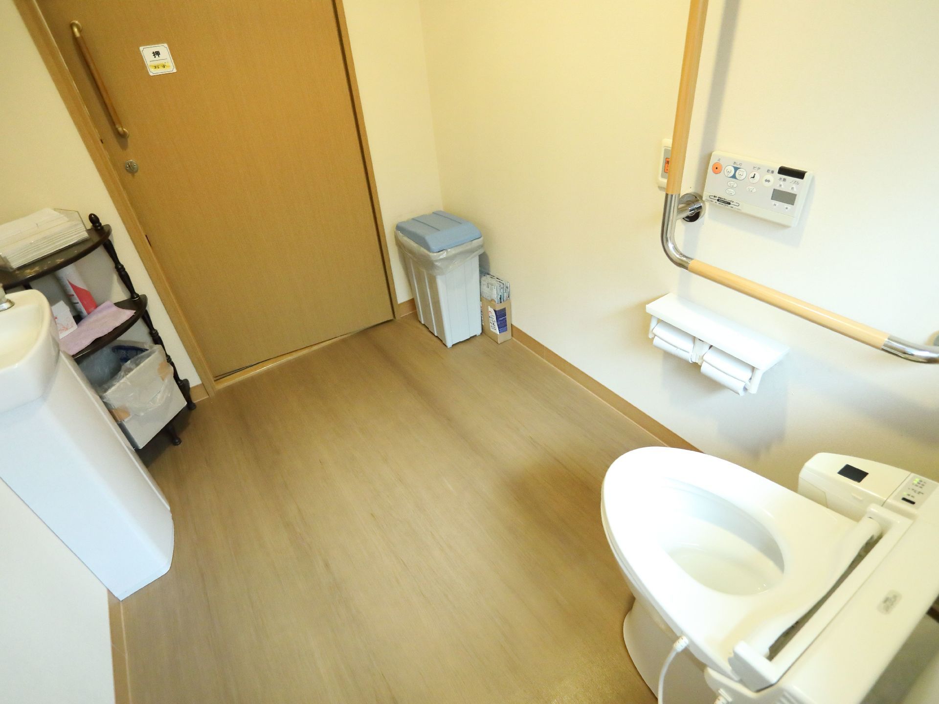 トイレには洋式便器が設置されている。便器の前方は広々としていて、手洗い器やペーパータオルが置かれている。