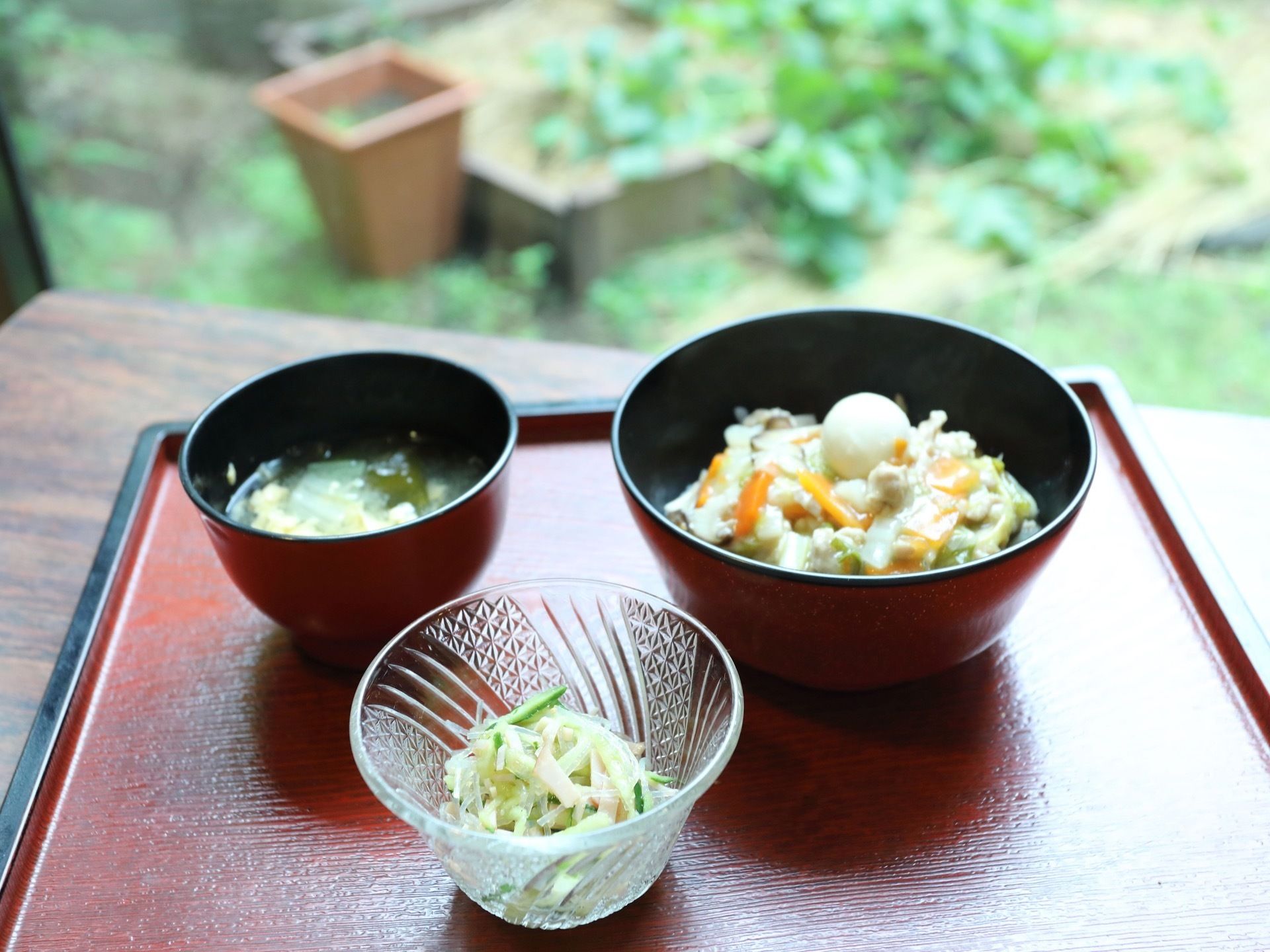 入居者様の食事がお盆に配膳されている。中華丼、春雨の和え物、お味噌汁の3品が用意されている。野菜が豊富である。