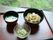 お盆には食事が並べられている。メインの中華丼の他に、春雨の和え物やお味噌汁がある。席からは外の景色が見える。