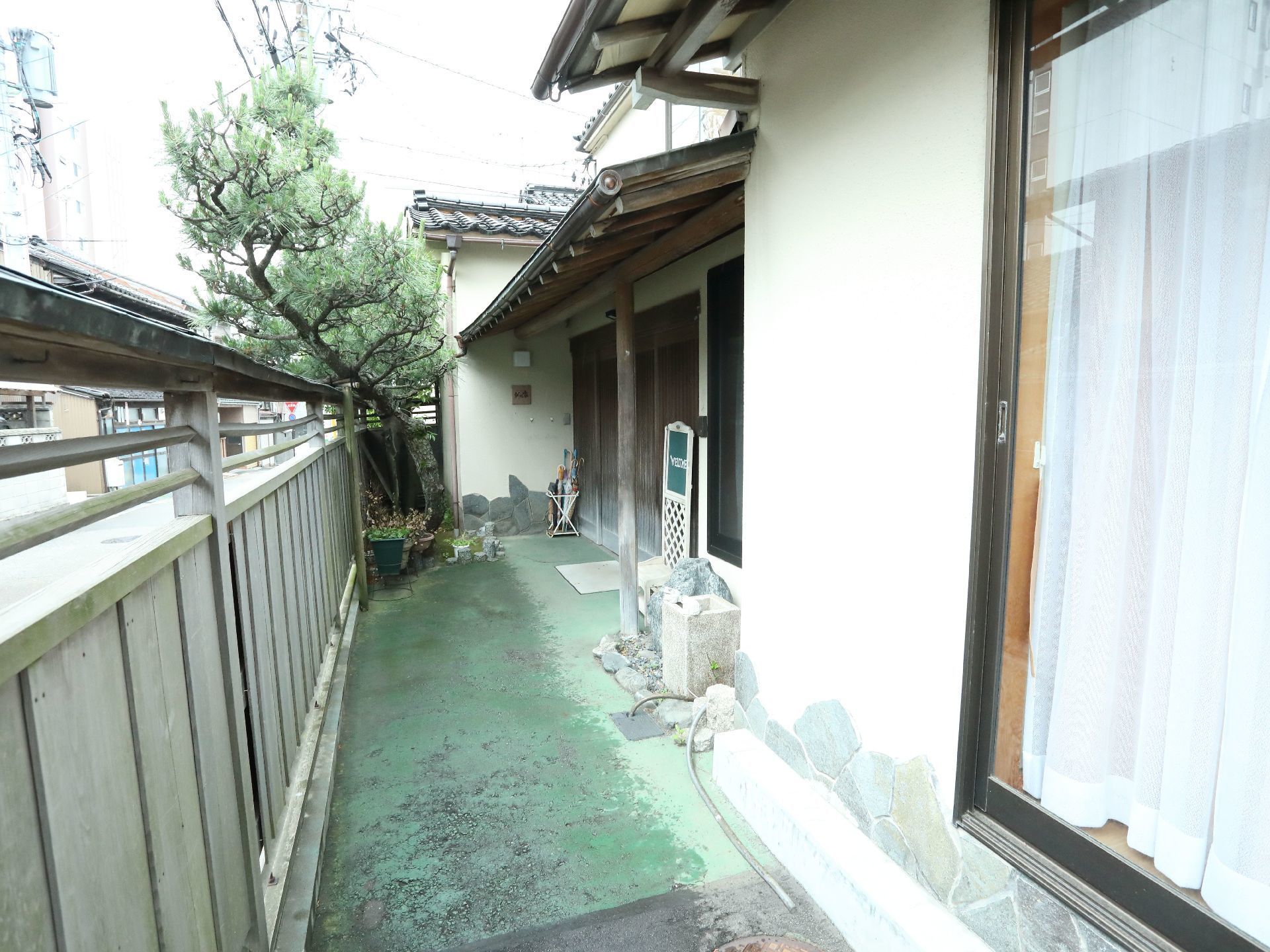 和風の佇まいの施設の周りは外部から見えないように囲われている。玄関には雨よけになる瓦屋根が付けられている。