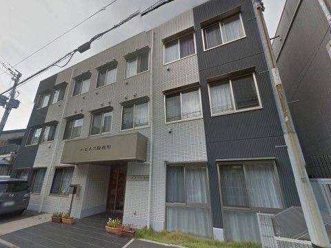 正面に窓が並んでいる3階建ての白と黒の配色がされた建物