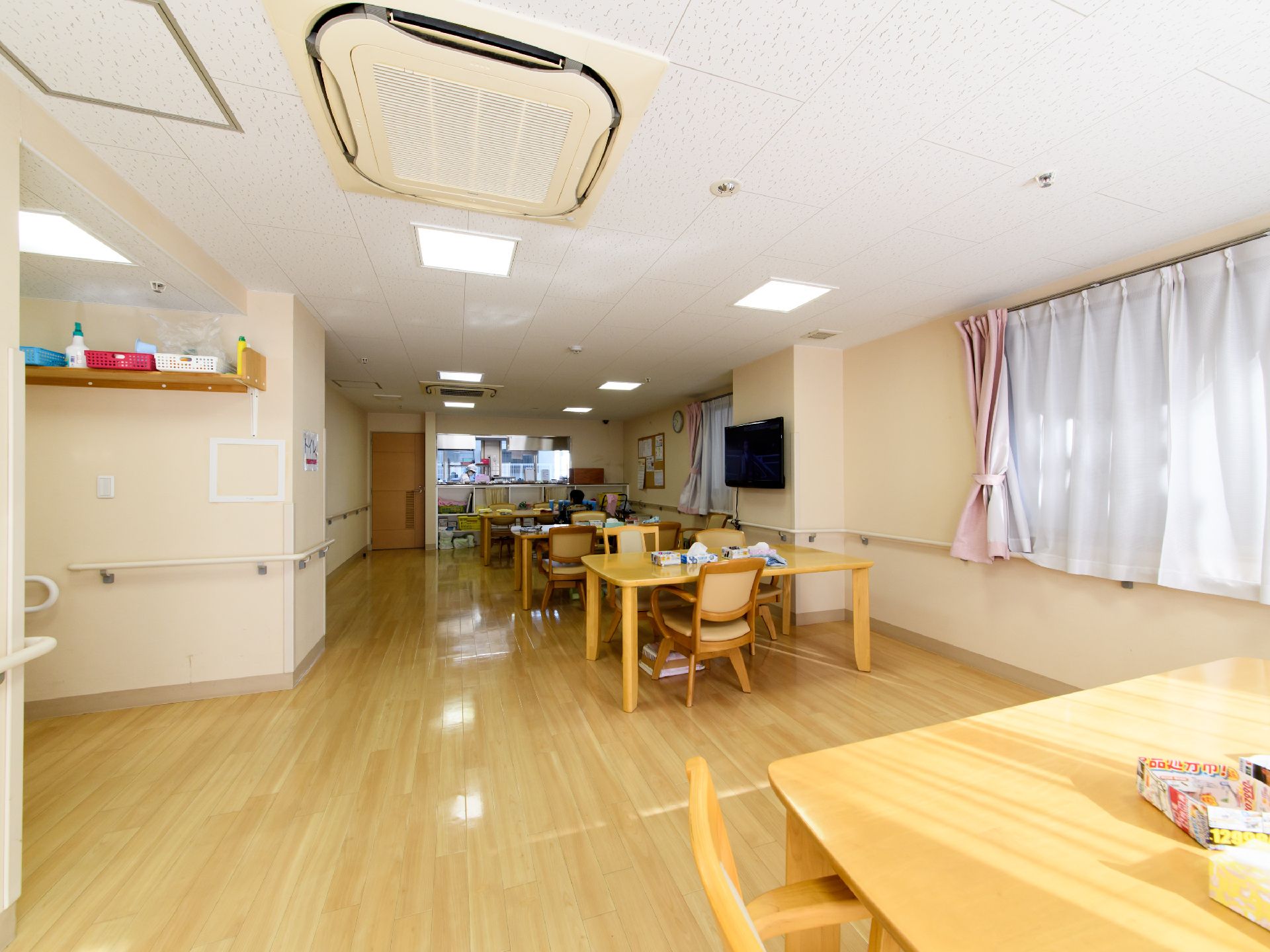 椅子とテーブルが並べられ、手すりが壁面に設置された広い共有スペース