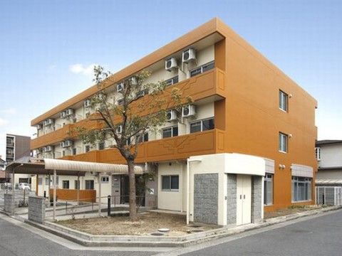 長い屋根のあるエントランスが特徴的なオレンジの建物
